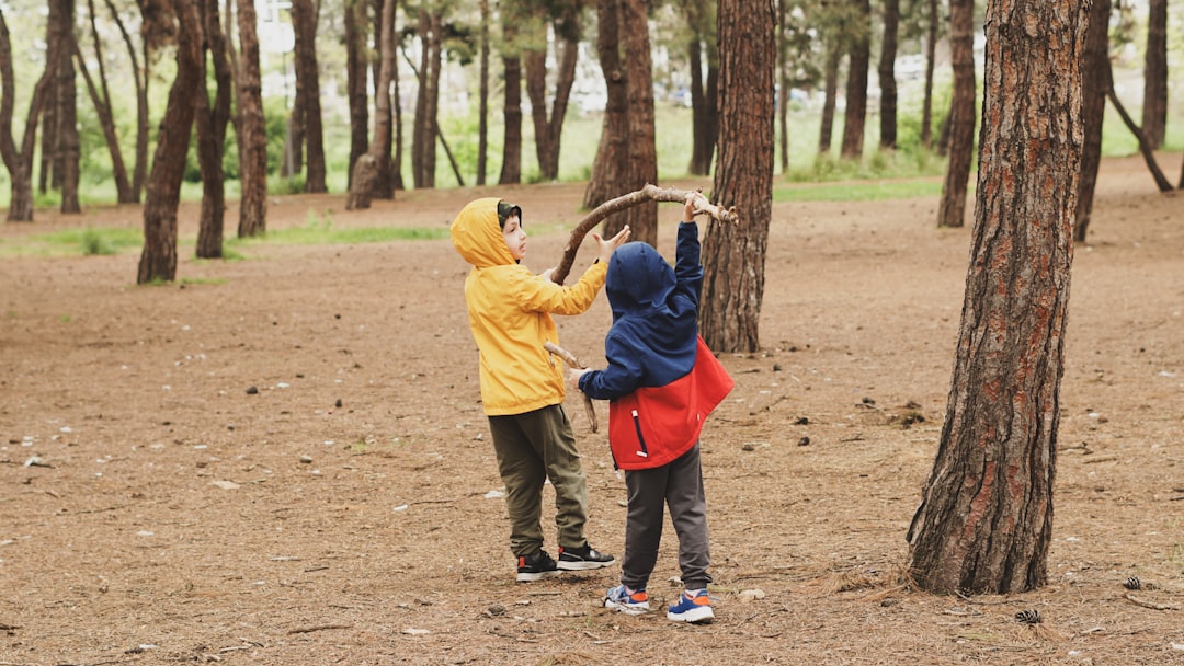 a-couple-of-kids-standing-next-to-each-other-in-a-forest-u-l75lnuahc