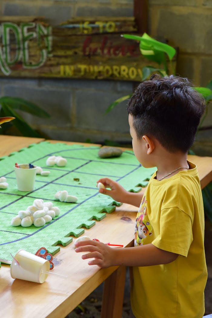 A young child focuses on a creative craft activity in an indoor setting, emphasizing fun learning.